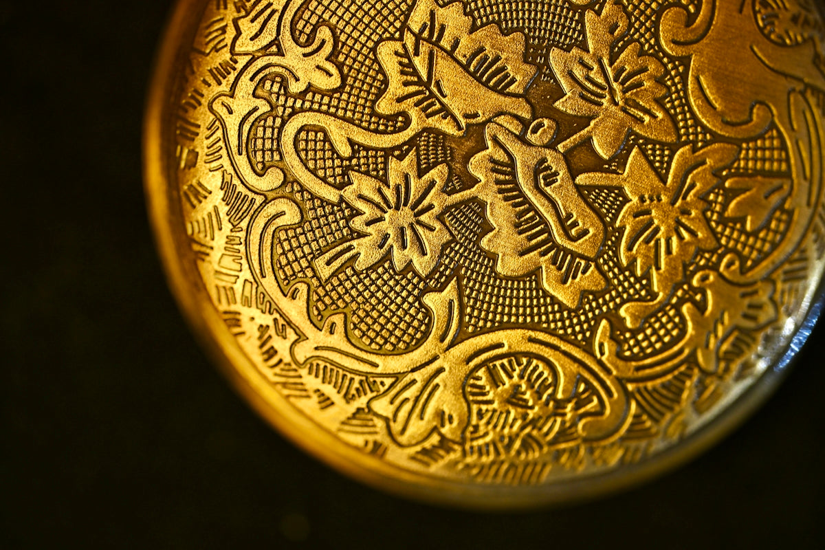 Close-up of ornate gold pocket watch engraving.